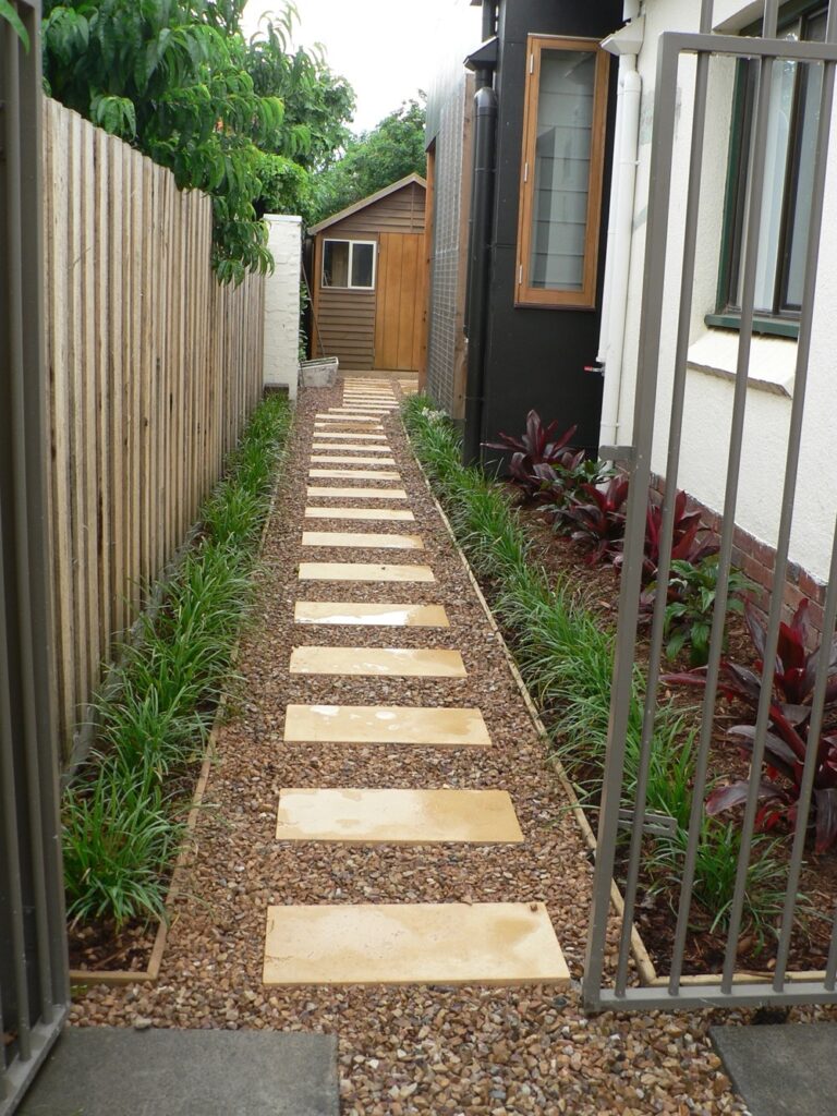 Gravel path with stepping stones through a landscaped side garden