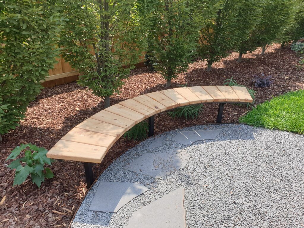 Curved timber bench and gravel stepping-stone area integrated into an established planted garden